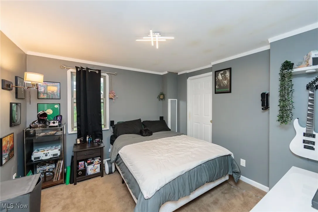 Bedroom with light carpet, crown molding, and baseboards