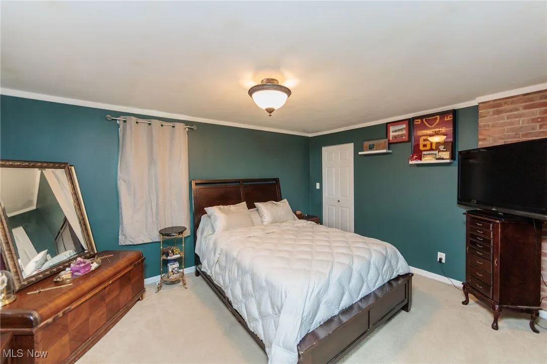 Bedroom featuring light carpet, baseboards, and crown molding