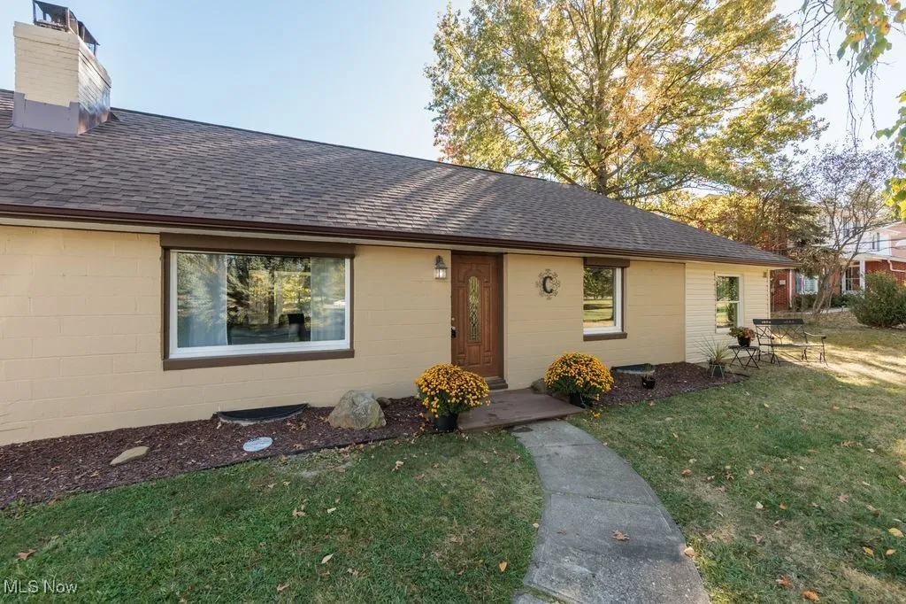View of front of property featuring roof with shingles, a front lawn, and concrete block siding
