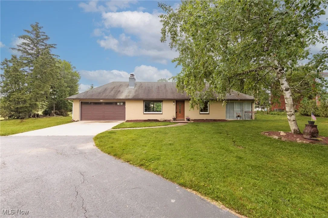 Ranch-style home with asphalt driveway, a garage, a front lawn, and a chimney