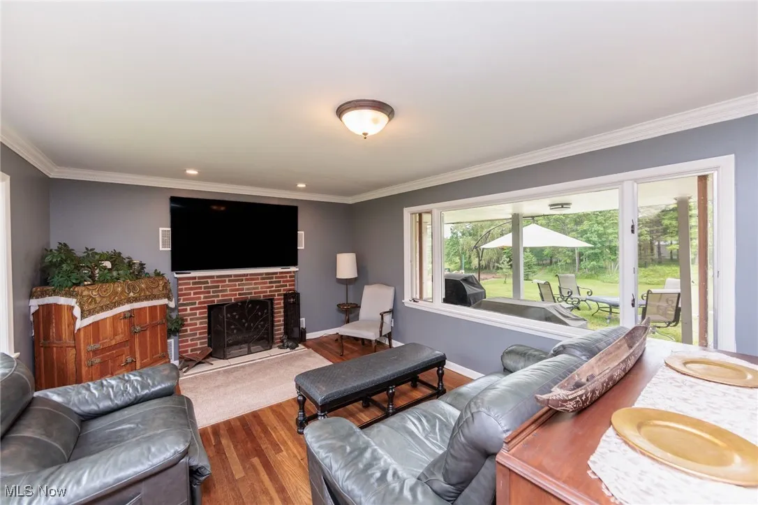 Living area featuring wood finished floors, crown molding, baseboards, and a fireplace