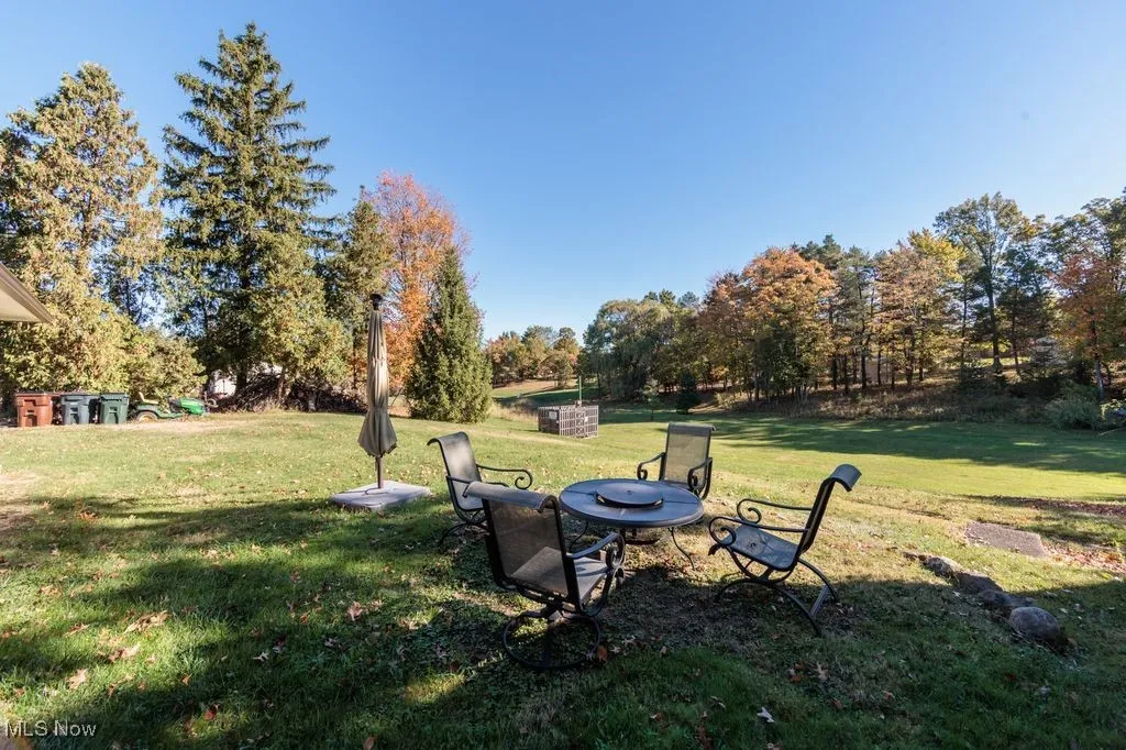 View of grassy yard with view of wooded area