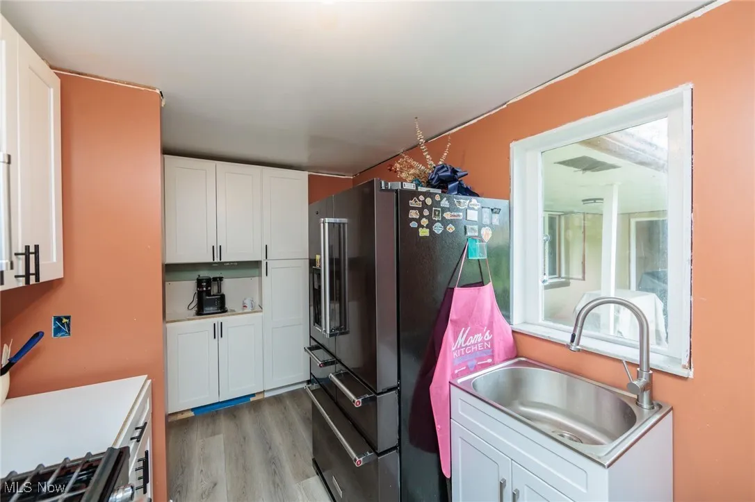 Kitchen featuring a sink, high end refrigerator, light wood finished floors, and white cabinets