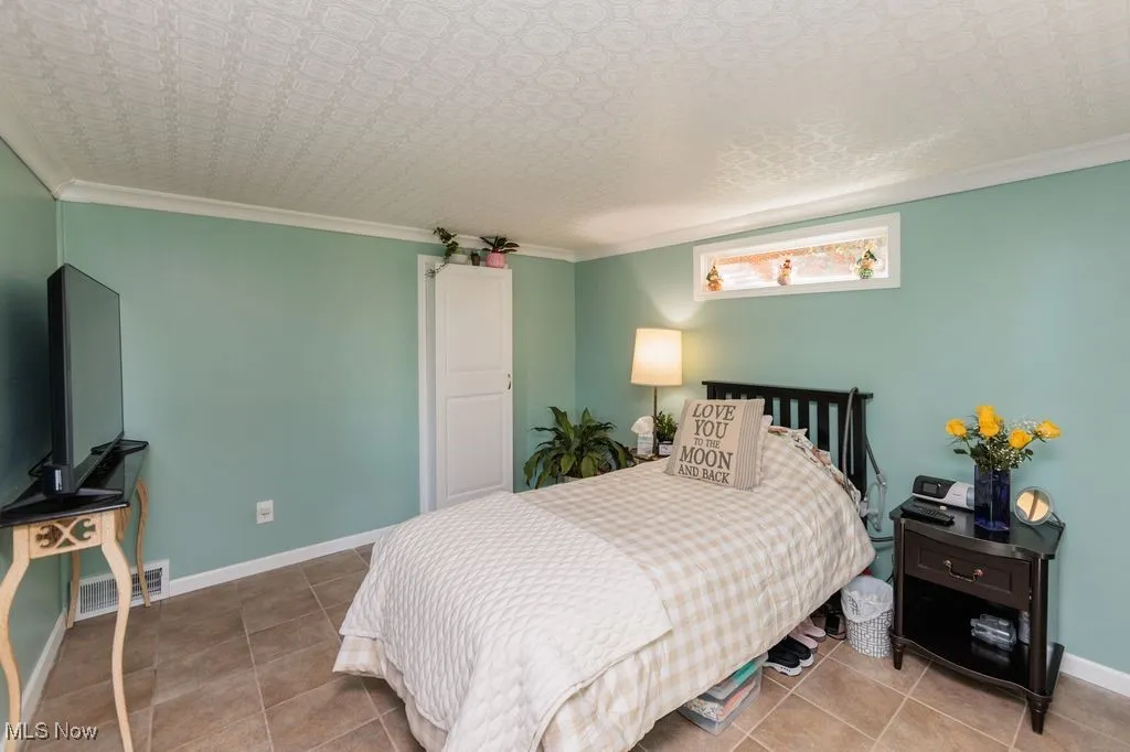 Bedroom with ornamental molding and tile patterned floors