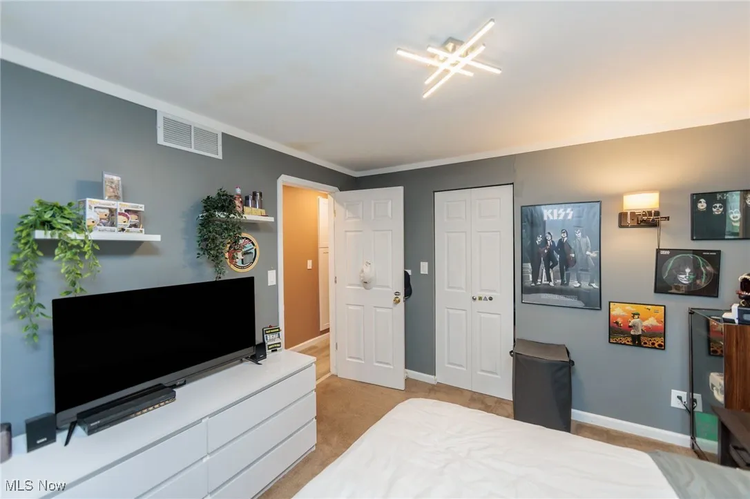 Carpeted bedroom featuring baseboards, a closet, and ornamental molding