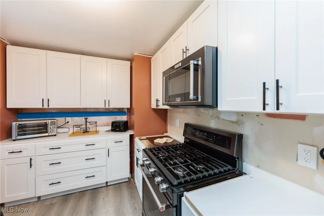 Kitchen with stainless steel gas range, light countertops, white cabinetry, and tasteful backsplash