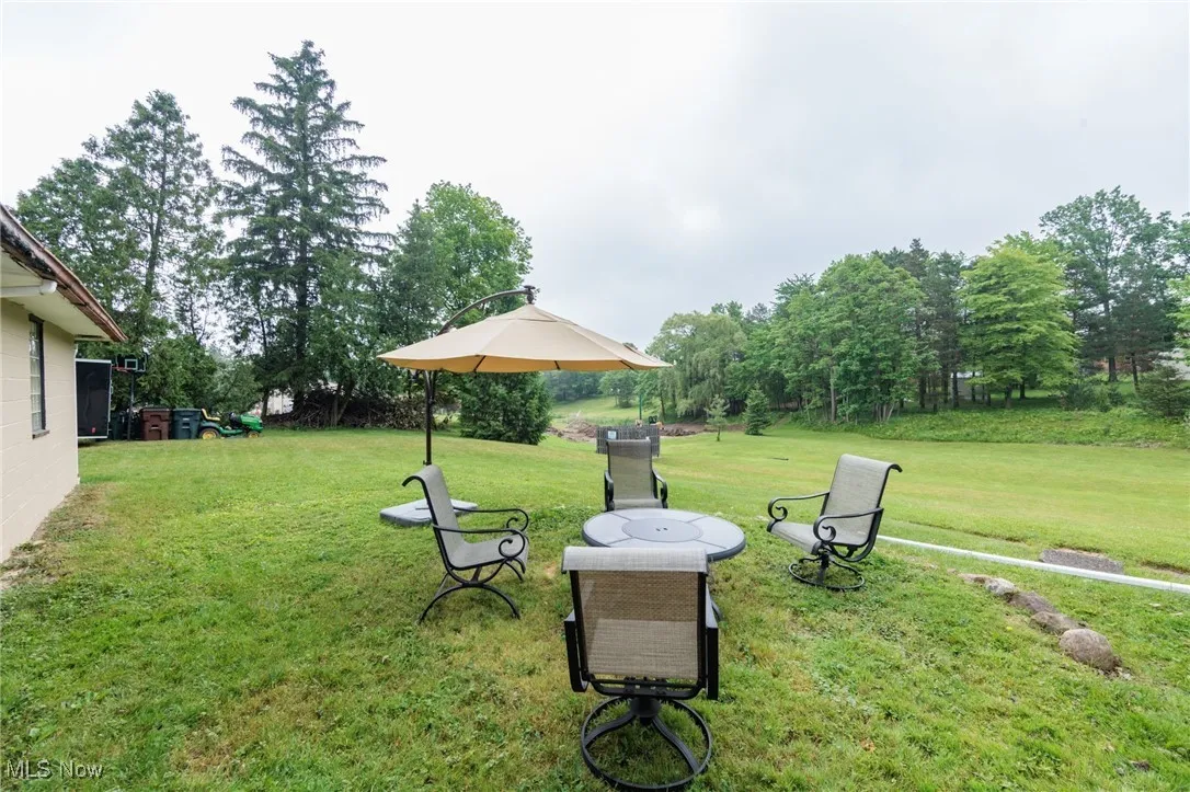 View of grassy yard featuring view of wooded area