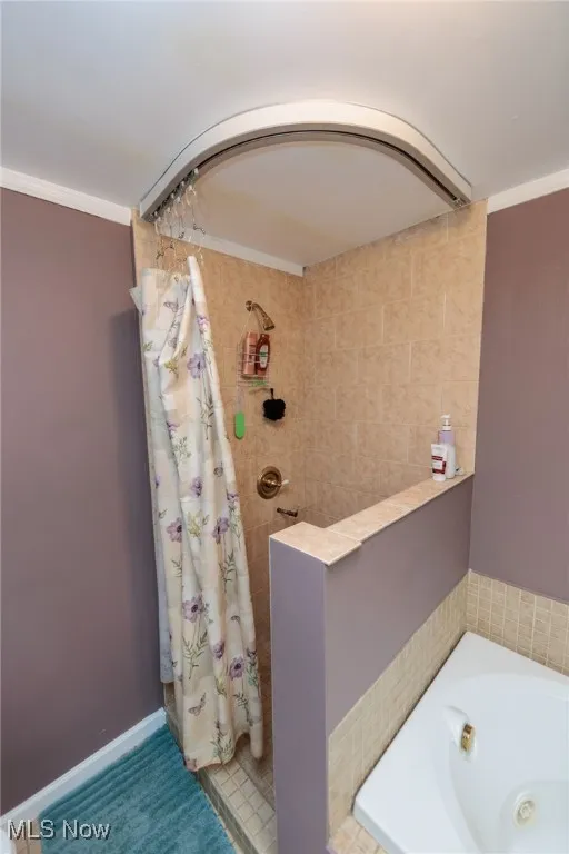 Bathroom featuring tiled shower, a jetted tub, and ornamental molding