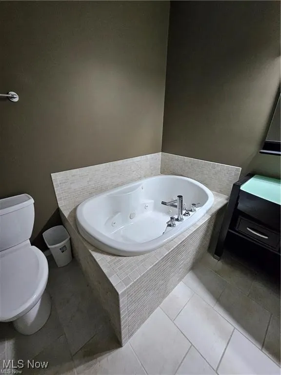 Full bathroom featuring toilet, a whirlpool tub, and tile patterned floors