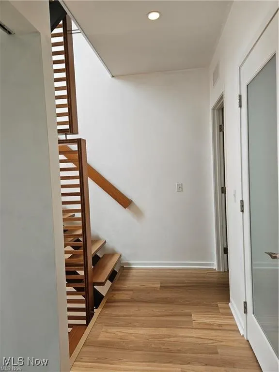 Stairs with wood finished floors, recessed lighting, and baseboards
