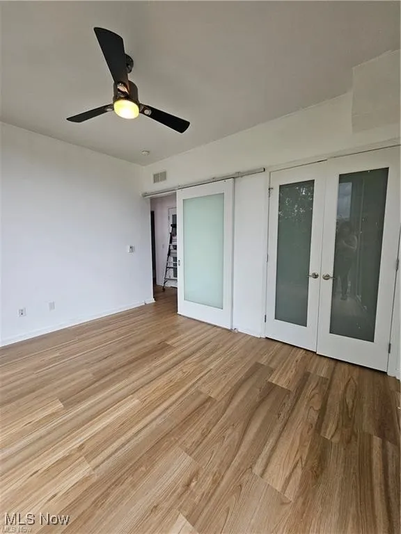 Spare room with light wood-type flooring, french doors, ceiling fan, and baseboards