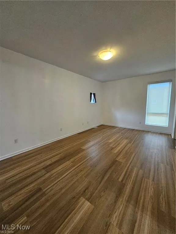Unfurnished room with dark wood-style flooring and baseboards