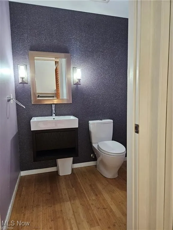 Bathroom with wood finished floors, toilet, vanity, and baseboards