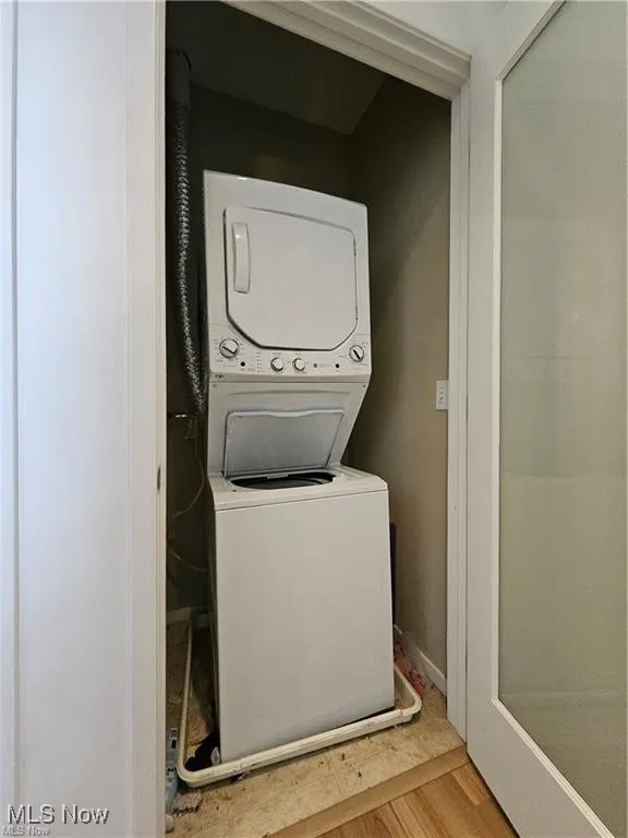 Laundry room featuring estacked washer and dryer and light wood-type flooring