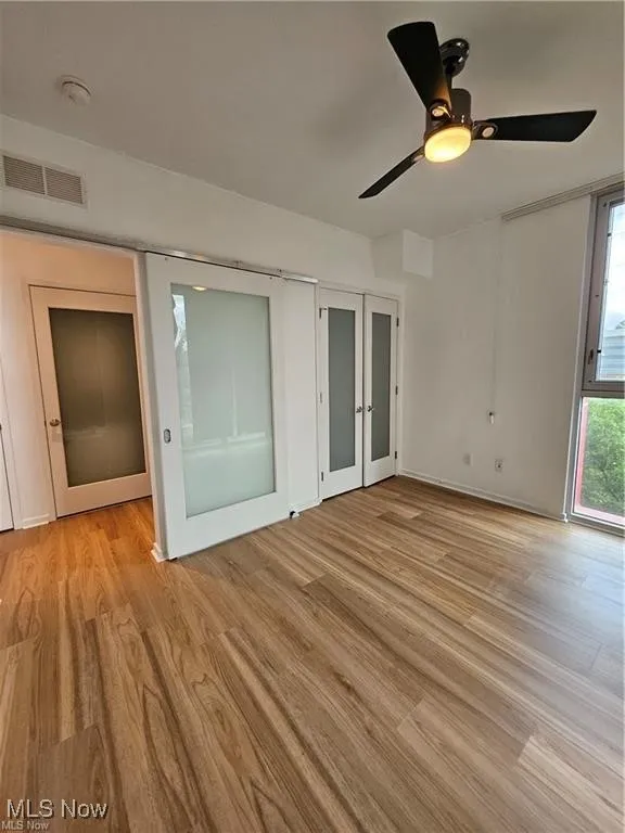 Spare room with light wood-style flooring, a ceiling fan, baseboards, a smoke detector, and french doors