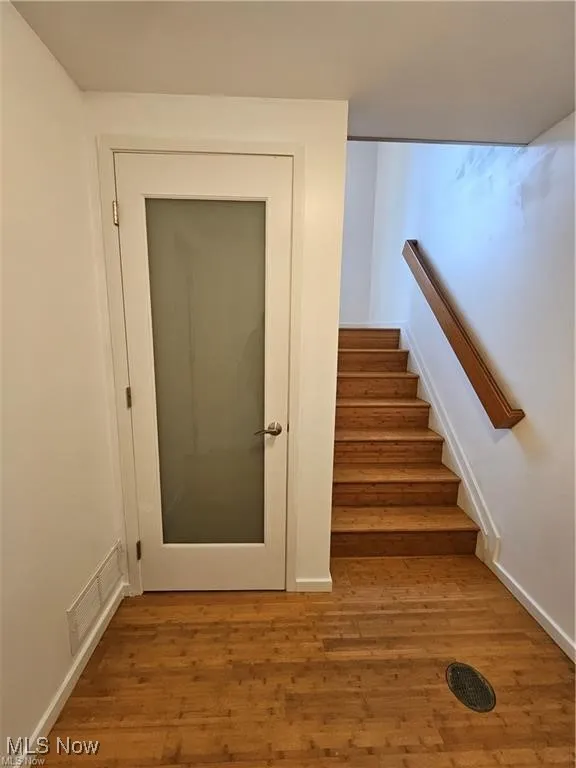 Stairs with wood finished floors and baseboards