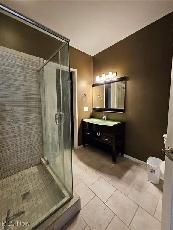 Bathroom with vanity, a shower stall, tile patterned flooring, toilet, and baseboards