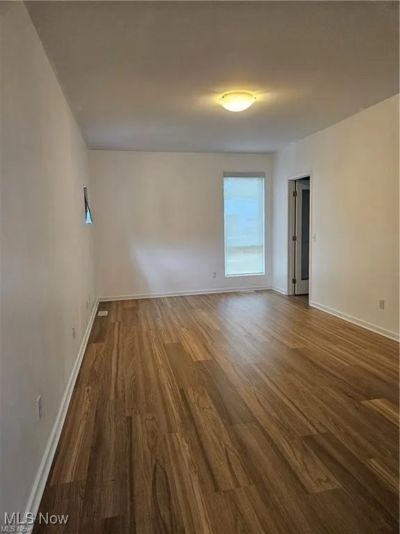 Spare room with dark wood finished floors and baseboards
