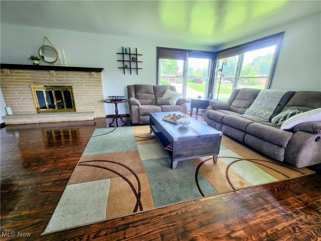 Living room with plenty of natural light, wood finished floors, and a brick fireplace