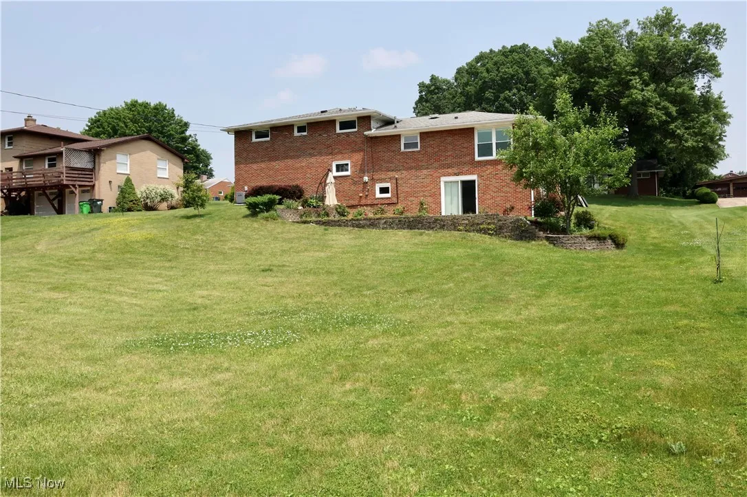 Back of house with brick siding and a yard