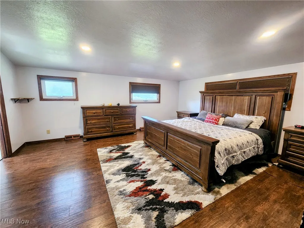 Bedroom featuring dark wood finished floors, baseboards, a textured ceiling, and recessed lighting