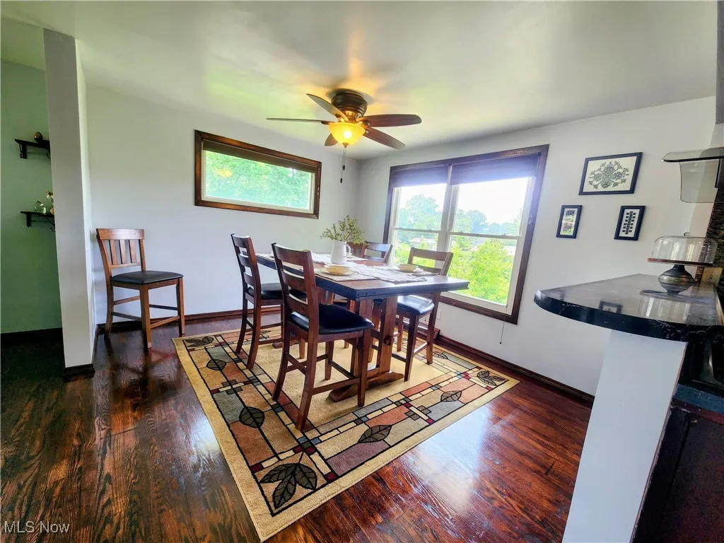 Dining area featuring dark wood finished floors, ceiling fan, and baseboards