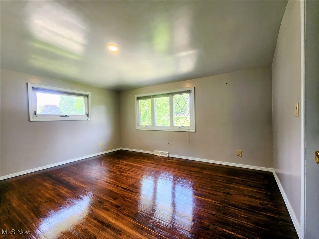 Unfurnished room with dark wood-style floors and baseboards
