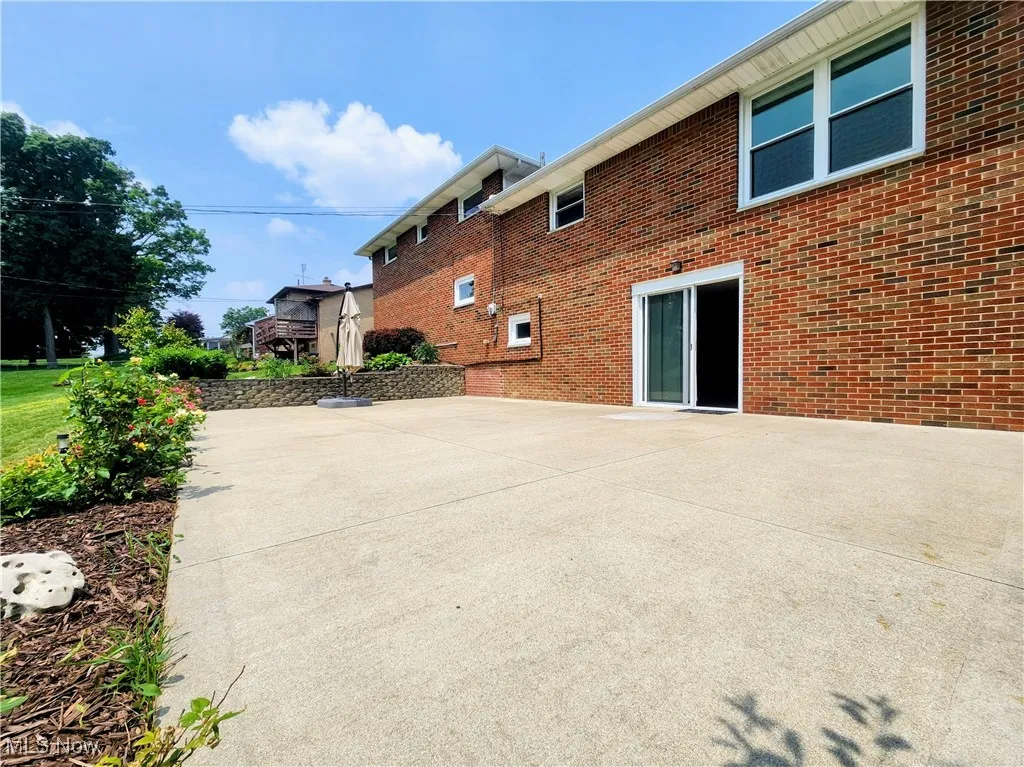 Rear view of property featuring brick siding and a patio area
