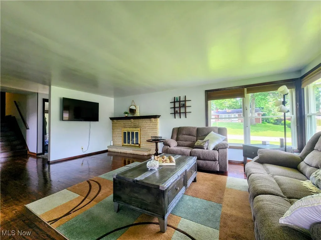 Living room with wood finished floors, a brick fireplace, and baseboards