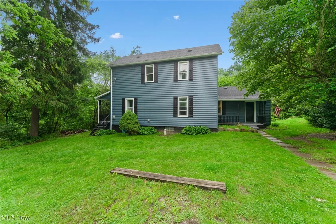 Rear view of property featuring a sunroom and a lawn