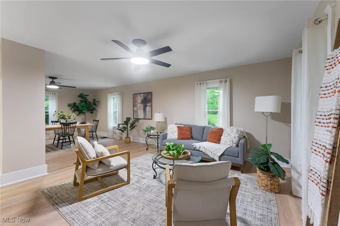 Living area with healthy amount of natural light, a ceiling fan, and light wood-type flooring
