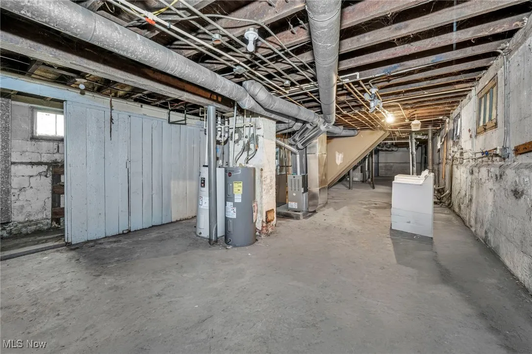 Below grade area with water heater, heating unit, and stairs