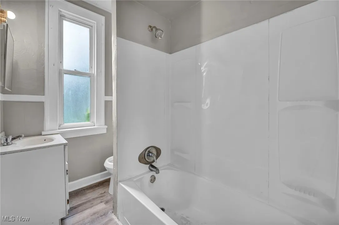 Bathroom with vanity, wood finished floors, and shower / washtub combination