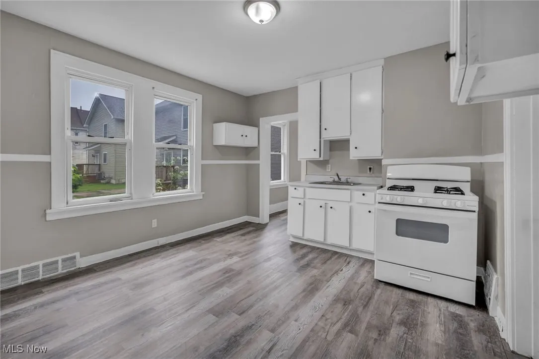 Kitchen with gas range gas stove, white cabinetry, plenty of natural light, and light wood-style floors