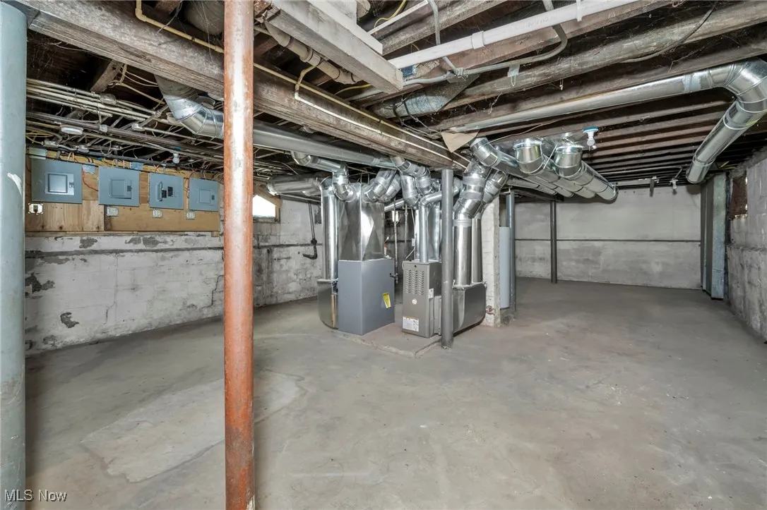 Unfinished below grade area with electric panel and heating unit