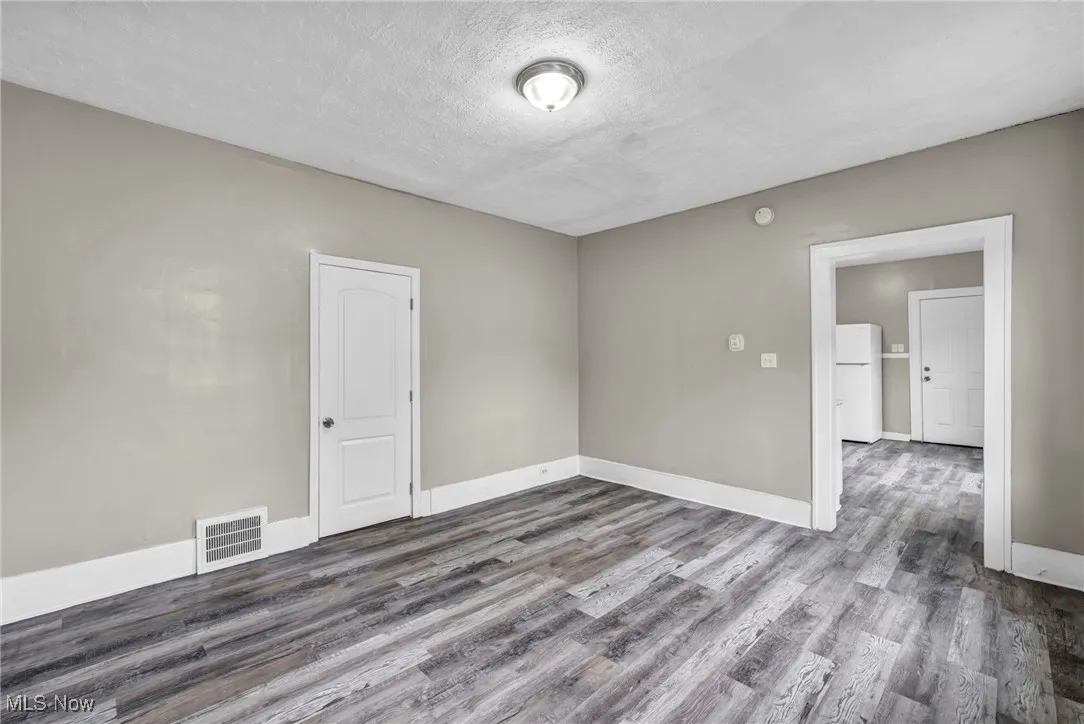 Spare room with dark wood finished floors, a textured ceiling, and a smoke detector