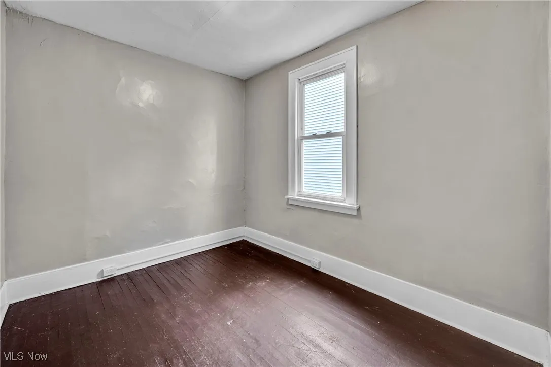 Unfurnished room featuring dark wood finished floors and baseboards