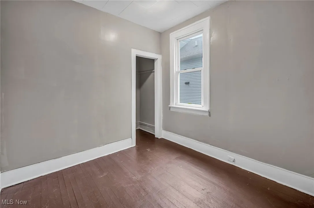 Unfurnished bedroom featuring dark wood-style flooring and a closet