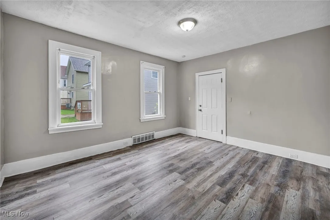 Spare room featuring wood finished floors, a textured ceiling, and plenty of natural light