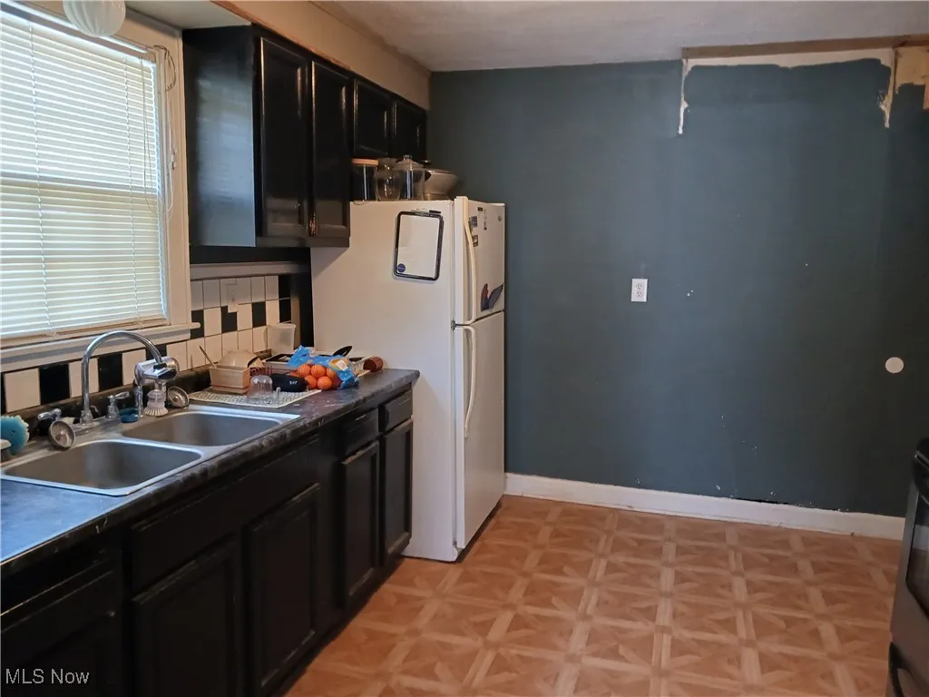 Kitchen with freestanding refrigerator, dark cabinetry, healthy amount of natural light, and dark countertops
