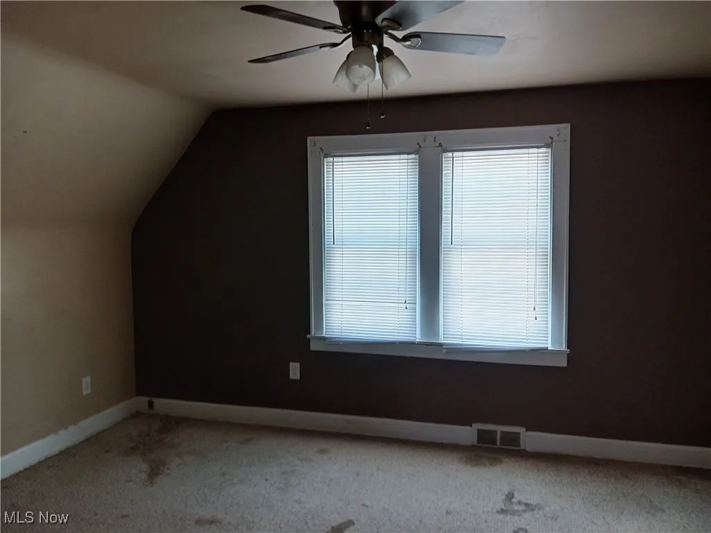  with ceiling fan, carpet flooring, and lofted ceiling