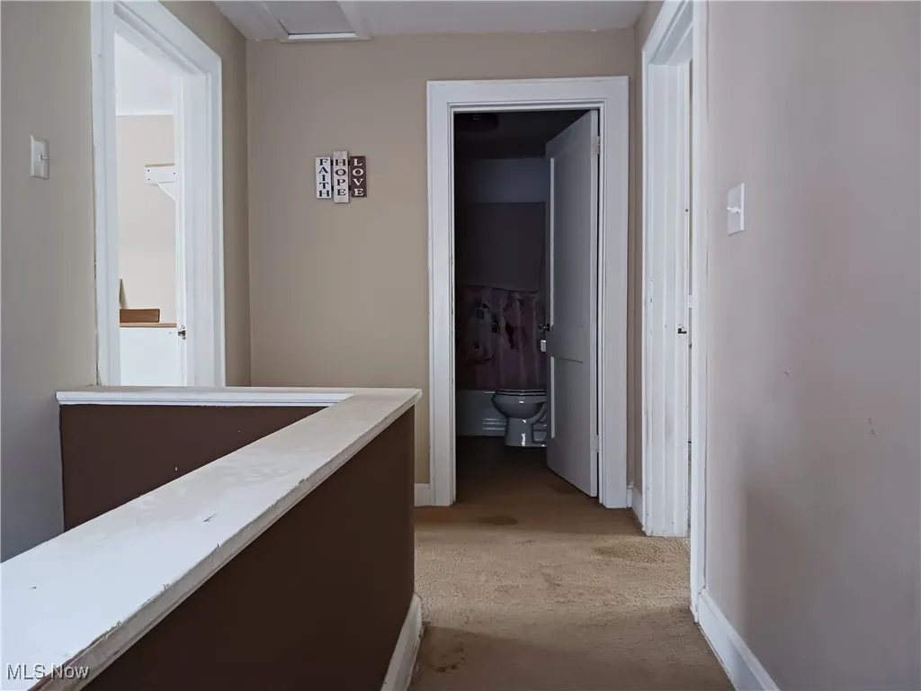 Hall featuring light colored carpet and baseboards