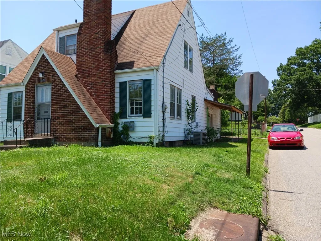 View of home's exterior with a chimney, a lawn, and a shingled roof