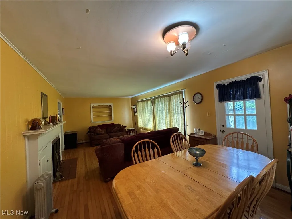 Dining space featuring radiator heating unit, wood-type flooring, a fireplace, and crown molding