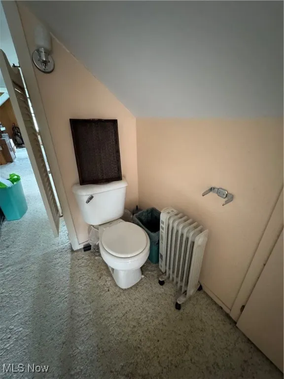 Bathroom with radiator, toilet, and lofted ceiling