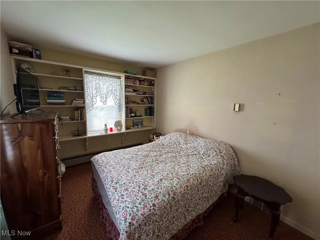 Carpeted bedroom featuring baseboard heating