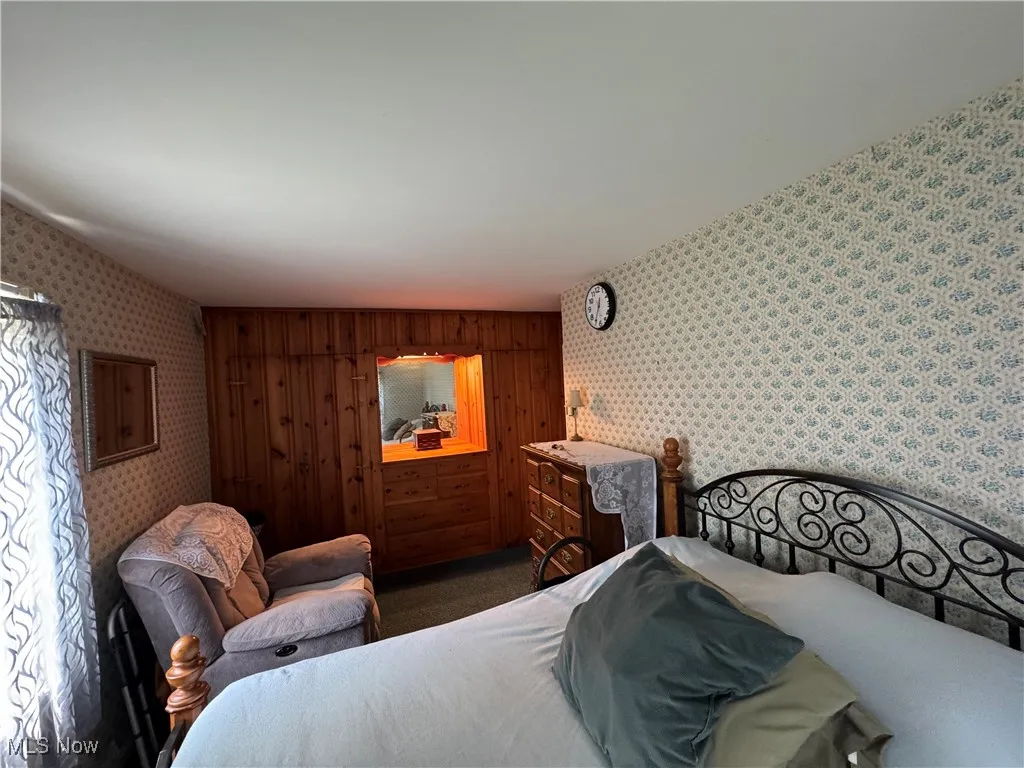 Carpeted bedroom featuring wallpapered walls