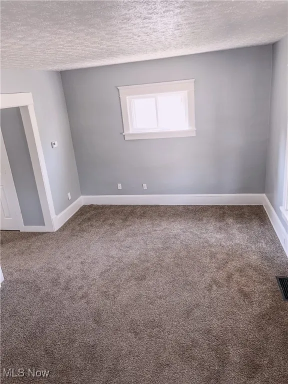 Carpeted living room with baseboards and a textured ceiling