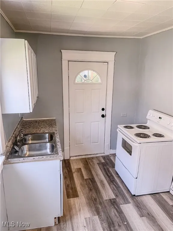 Kitchen featuring white range with electric cooktop, white cabinets, dark wood finished floors, and crown molding