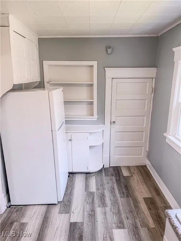 Kitchen with freestanding refrigerator, wood finished floors, ornamental molding, and open shelves